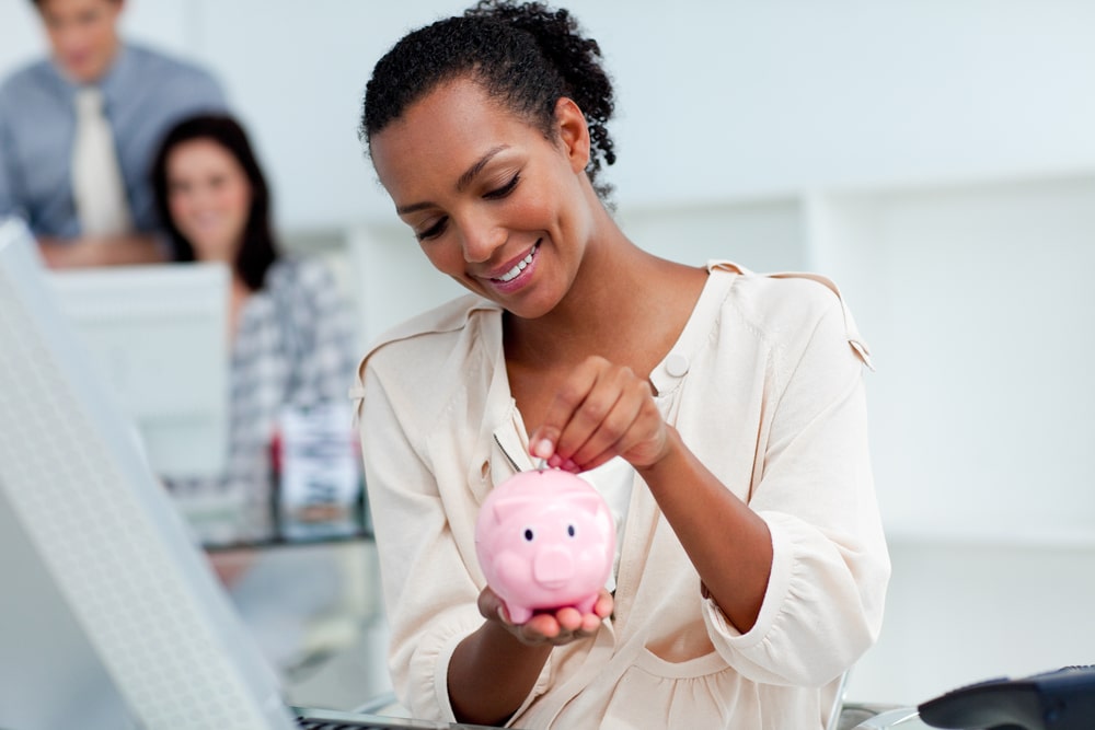 mulher colocando dinheiro no porquinho para ilustrar texto sobre o que é educação financeira