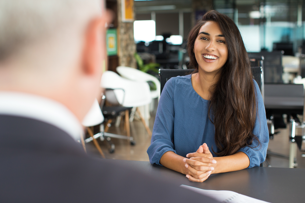 mulher sorrindo em entrevista de emprego para ilustrar texto sobre salário