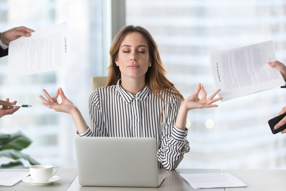 mulher no escritório com as mãos fazendo OK para simular texto sobre tolerância ao estresse