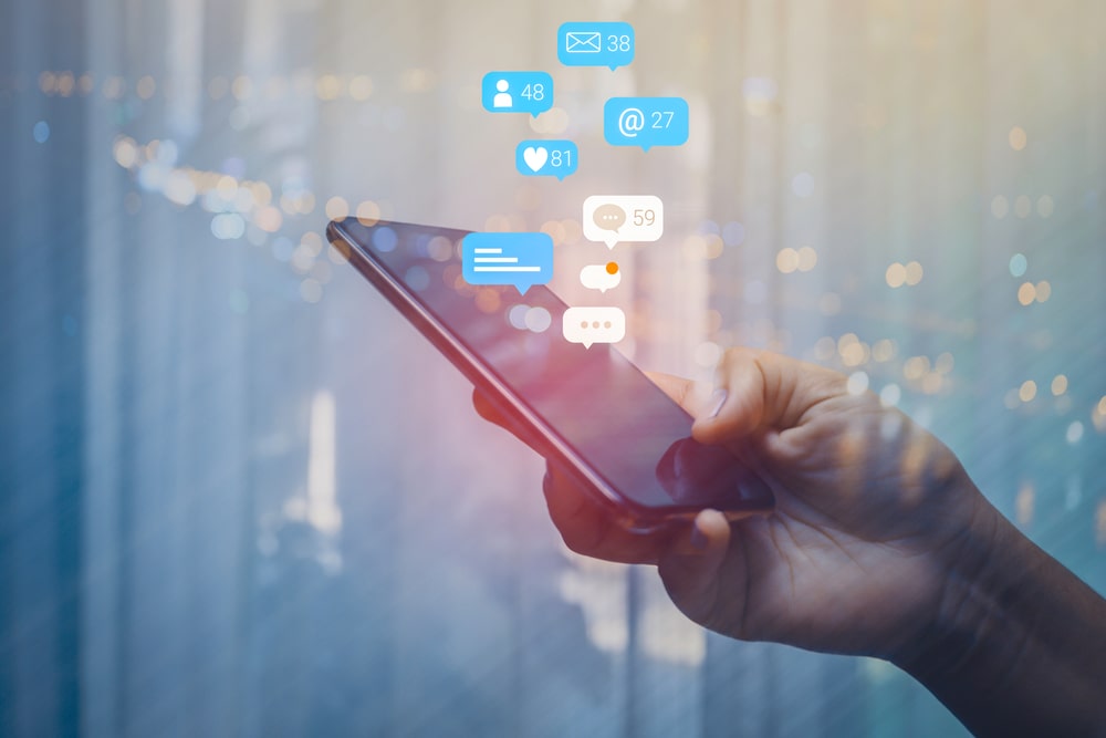celular na mão com ícones de redes sociais para ilustrar texto sobre oportunidade de emprego