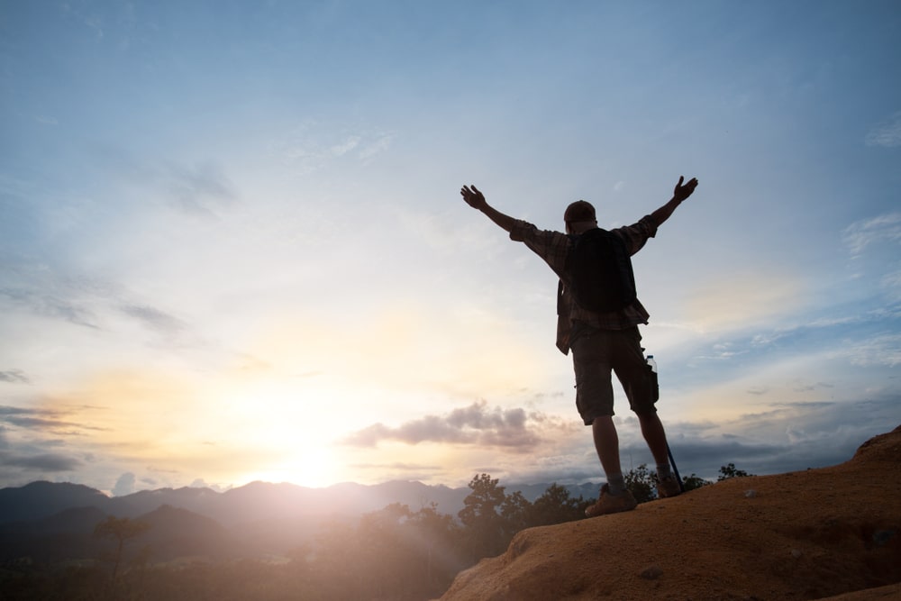 imagem de um homem em cima de uma montanha para ilustrar o texto de como ser bem sucedido
