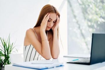 mulher com as mãos na cabeça para ilustrar texto sobre alimentos que reduzem o estresse no ambiente de trabalho