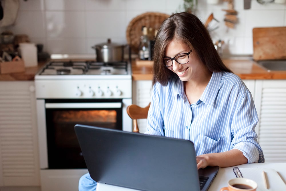 mulher com notebook na cozinha para ilustrar texto sobre o Ambiente Virtual de Aprendizagem da pós-graduação