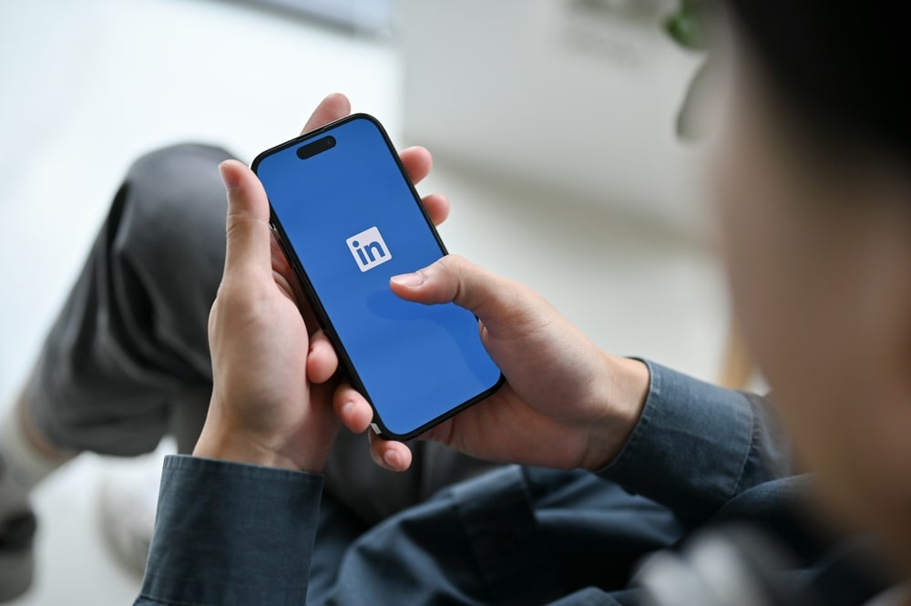 celular com LinkedIn para ilustrar texto sobre como fazer um resumo profissional no LinkedIn