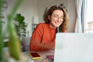 mulher sorrindo com notebook para ilustrar texto sobre pós-graduação com TCC opcional