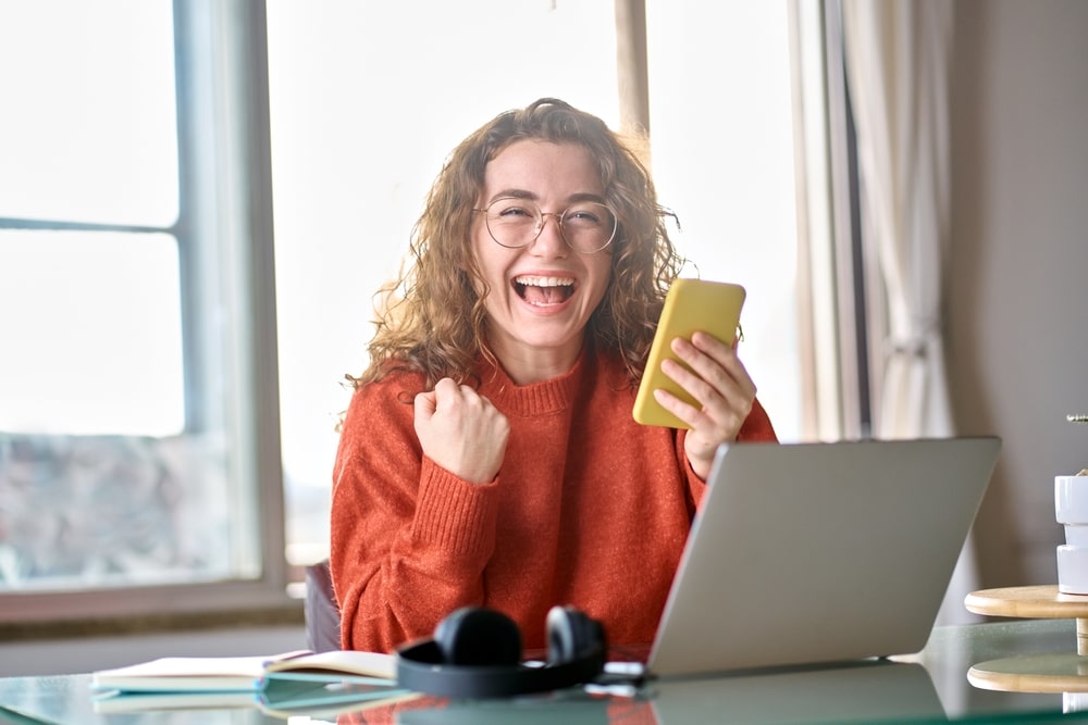 mulher feliz comemorando para ilustrar texto sobre e-mail de aprovação em processo seletivo
