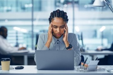 mulher com expressão de dor de cabeça para ilustrar texto sobre desgaste no trabalho