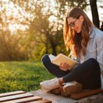 mulher ao ar livre lendo livro para ilustrar texto sobre livros para crescimento pessoal