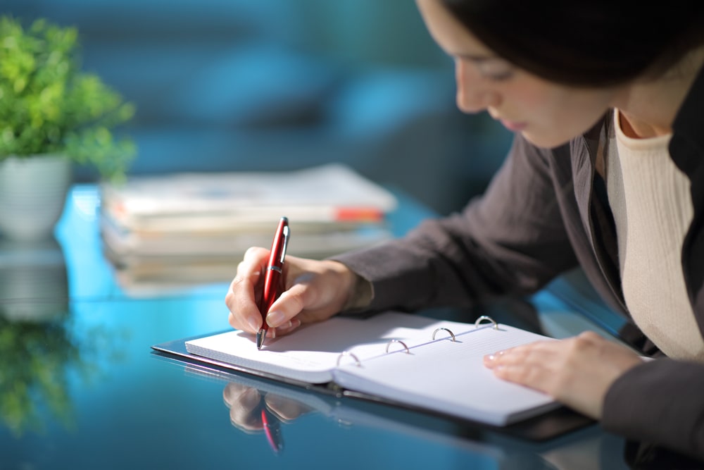 mulher fazendo anotações no caderno para ilustrar planejamento da carreira