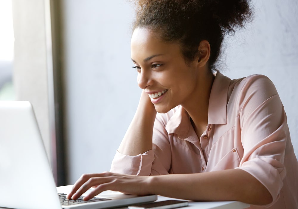 mulher feliz com notebook para ilustrar texto sobre como colocar no LinkedIn que estou estou procurando emprego