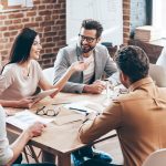 equipe reunida em uma mesa no escritório para ilustrar conteúdo sobre como se adaptar ao novo emprego