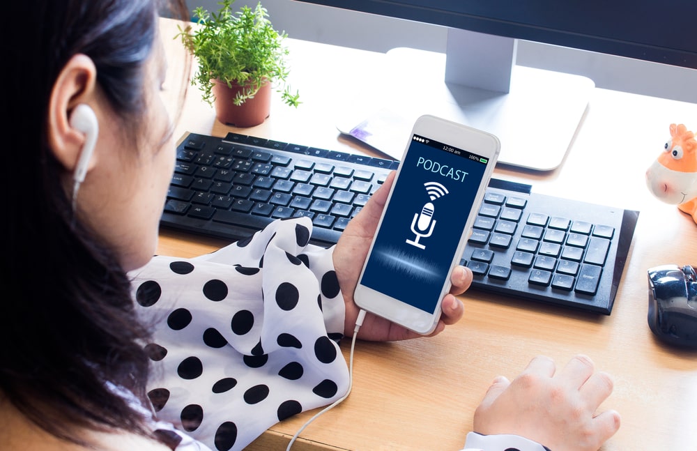 mulher com celular na mão ouvindo podcasts sobre carreira