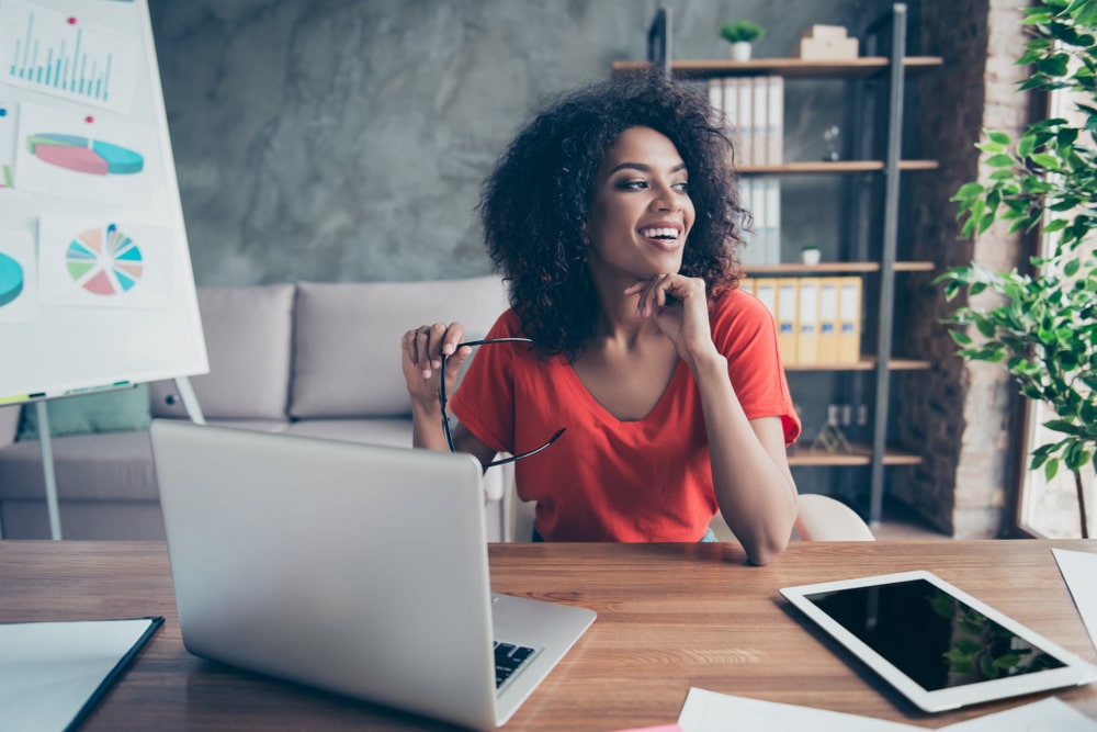 mulher sorrindo no escritório para ilustrar texto sobre significado de profissional qualificado