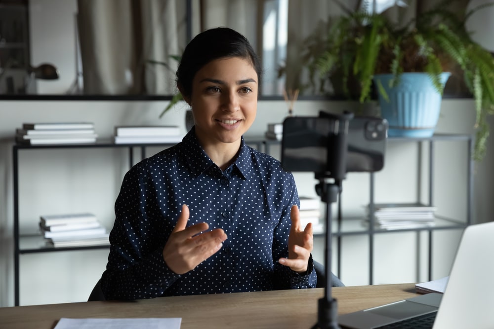 Mulher gravando vídeo com celular no tripé para ilustrar conteúdo sobre como fazer um vídeo de apresentação para emprego