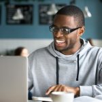 homem sorrindo olhando para o notebook para ilustrar texto sobre por que é importante estudar