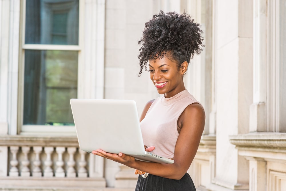 mulher sorrindo com notebook na mão para ilustrar texto sobre mentalidade empreendedora