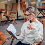 mulher lendo livro com café na mão para ilustrar texto sobre habilidade de negociação