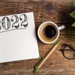 Imagem com uma mesa, um bloco de notas, café, um lápis e um óculos para ilustrar o texto de realização profissional