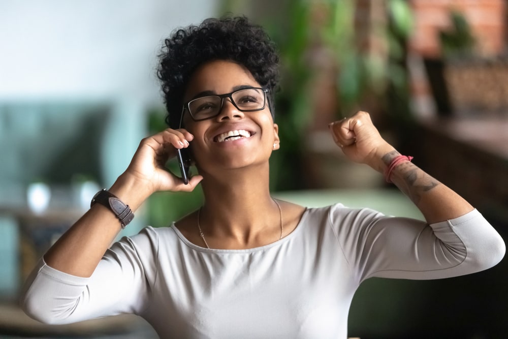 mulher em ligação com expressão de felicidade para ilustrar texto sobre trabalhar em grandes empresas