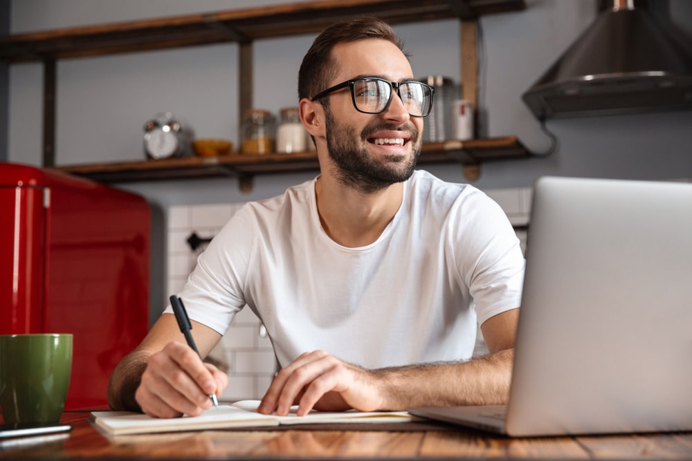 homem sorrindo e estudando online para ilustrar texto sobre como fazer pós-graduação