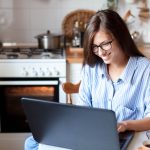 mulher com notebook na cozinha para ilustrar texto sobre o Ambiente Virtual de Aprendizagem da pós-graduação