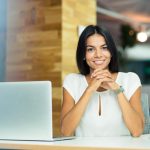 mulher sorrindo com notebook para ilustrar texto sobre nível de senioridade