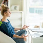 mulher meditando em ambiente de escritório para ilustrar texto sobre equilíbrio emocional no trabalho