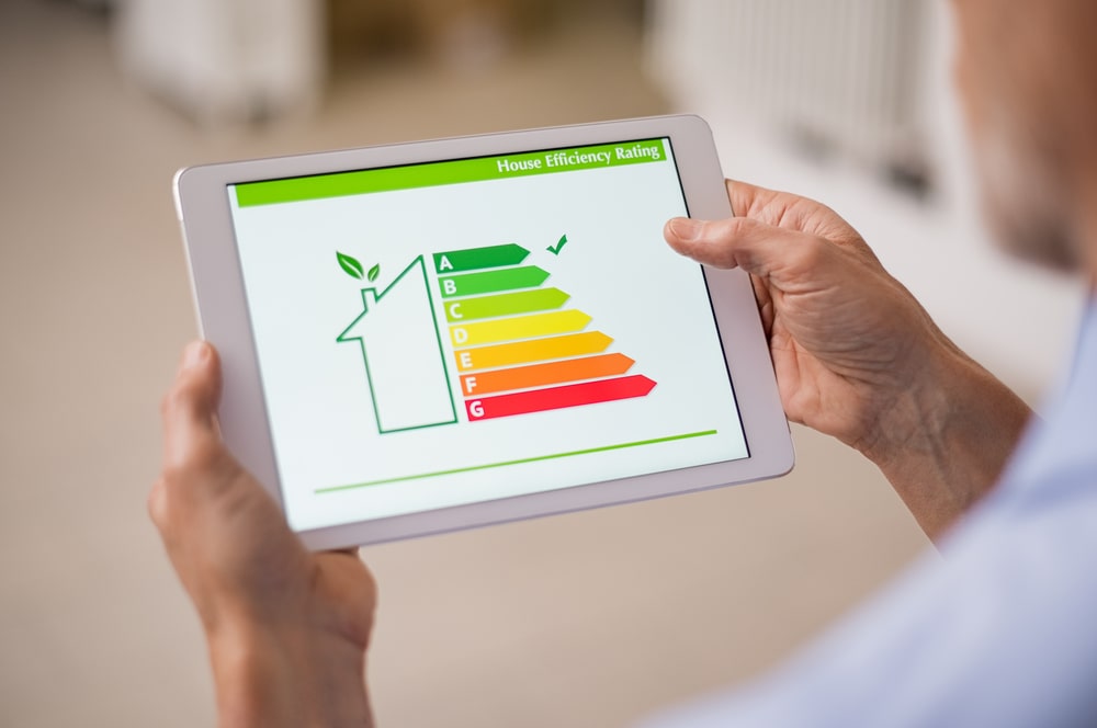 Mão segurando tablet digital e olhando para a classificação de eficiência da casa para ilustrar texto sobre especialização em eficiência energética