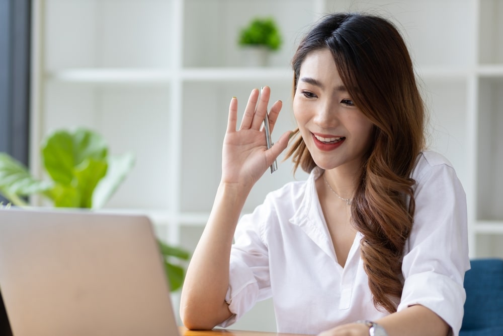 mulher com mão levantada na frente do notebook para ilustrar texto sobre perguntas para fazer para o recrutador