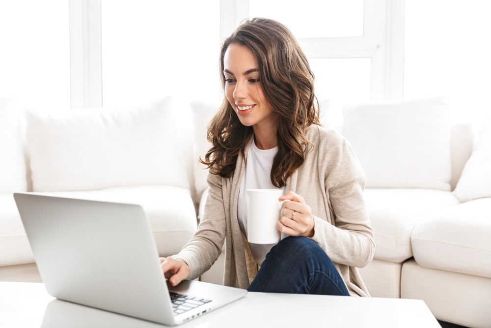 mulher com xícara na mão e notebook para representar texto sobre pós-graduação online em 4, 6 e 10 meses