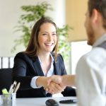 pessoas felizes dando a mão no escritório para representar texto sobre presença positiva na entrevista