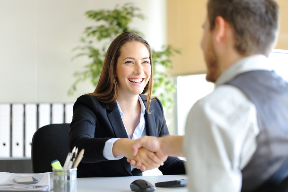 pessoas felizes dando a mão no escritório para representar texto sobre presença positiva na entrevista