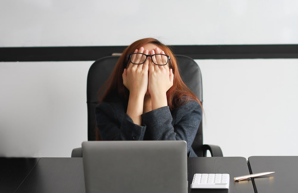 mulher com as mãos no rosto para ilustrar texto sobre incerteza no ambiente de trabalho