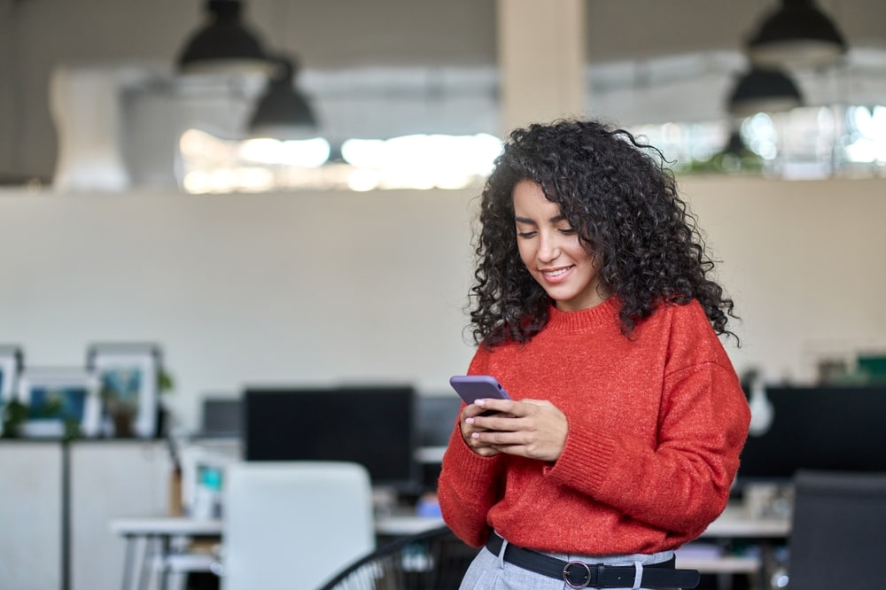 mulher com celular na mão para ilustrar texto sobre como fazer um post no LinkedIn