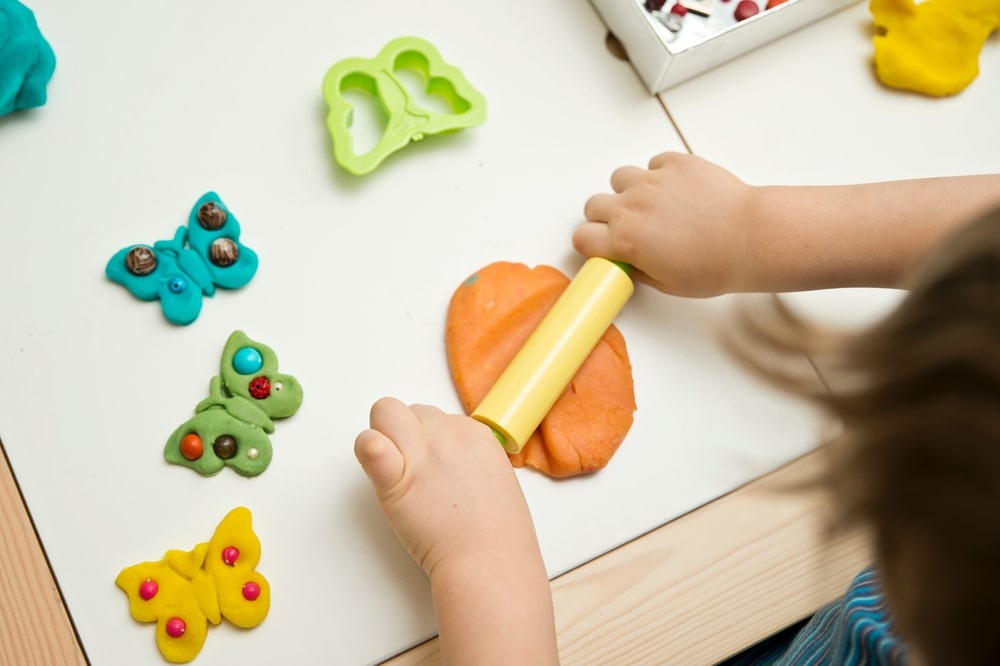 criança brincando com massinha para ilustrar texto sobre a importância da arte na Educação Infantil