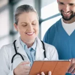 médica mostrando algo a dois colegas em tablet