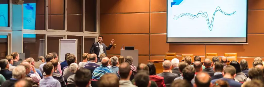 palestrante em auditório mostrando gráfico