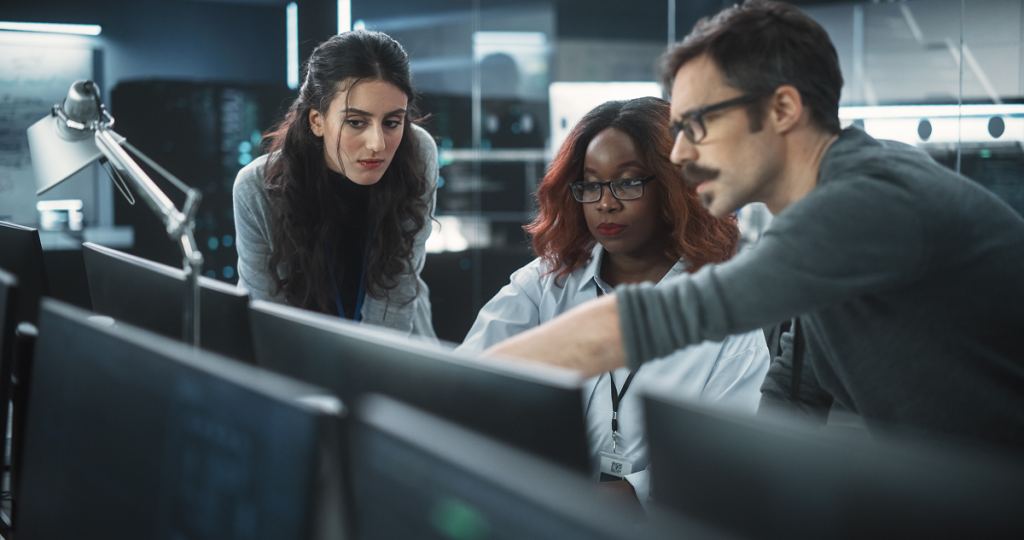 Empatia vs. Algoritmo: as soft skills resistem à IA? 1 Colegas de trabalho conversando em frente ao computador. Soft skills vs inteligência artificial.